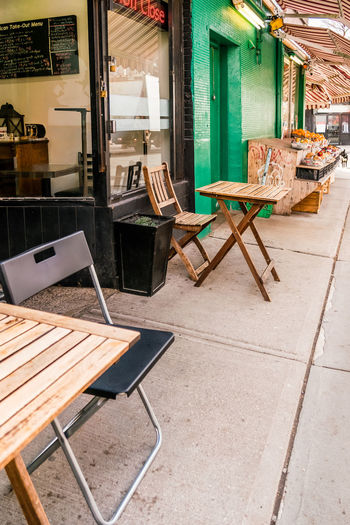 Empty chairs and tables in cafe against building