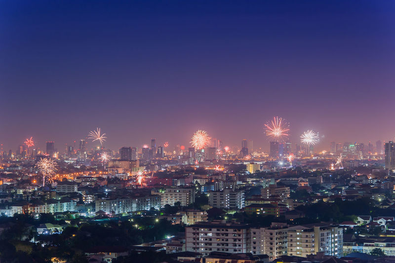 Firework exploding over illuminated cityscape at night