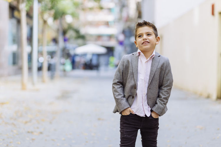 Boy looking away while standing on road