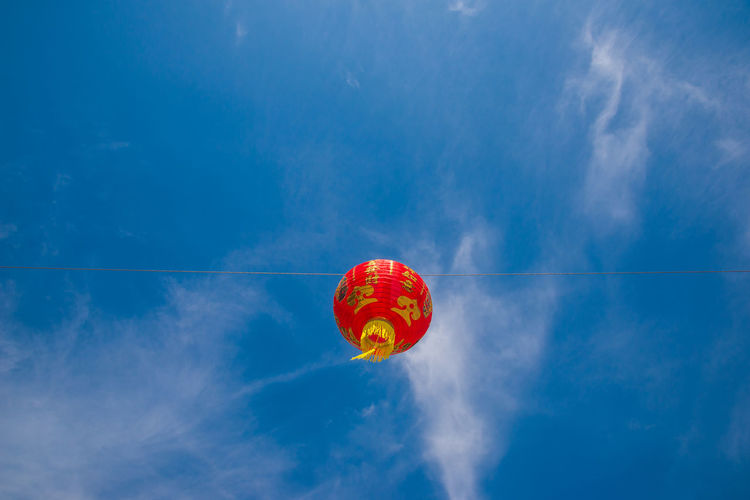 Low angle view of lantern hanging against blue sky