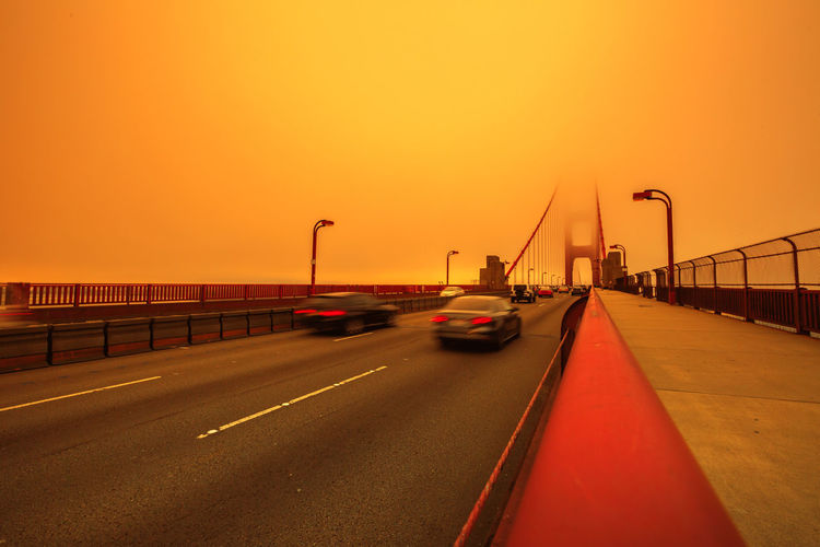 Vehicles on road against orange sky