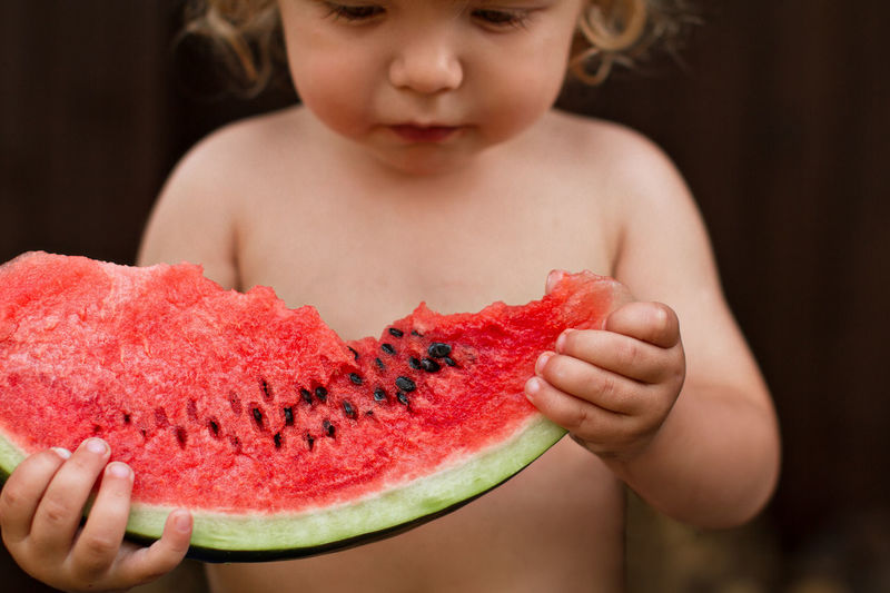 Midsection of cute boy eating watermelon sitting outdoors