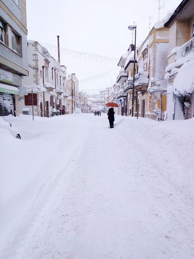 People on snow covered road in city