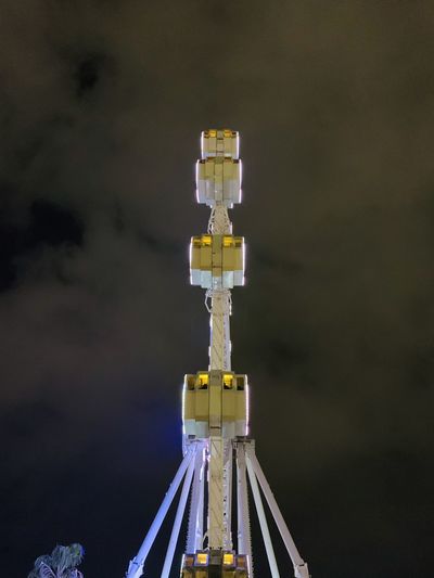 Low angle view of illuminated ferris wheel against sky at night, from a different perspective.