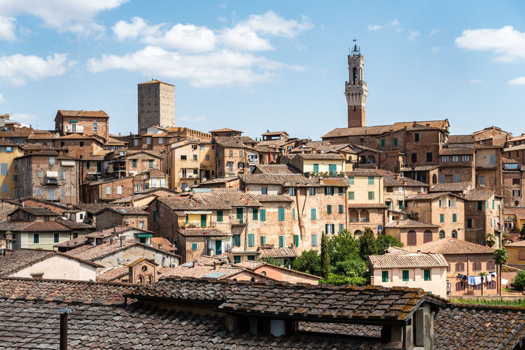 Scenic roofs of siena historic center with the iconic torre del mangia on the right, tuscany, italy