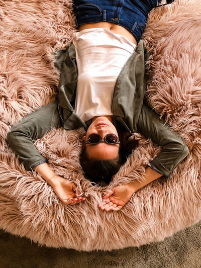 Smiling woman lying on fur cushion 