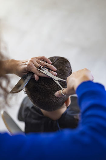 Cropped hand of barber cutting hair at salon