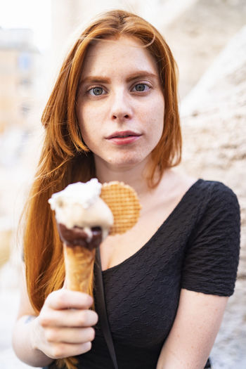 Ginger woman with ice cream looking at camera
