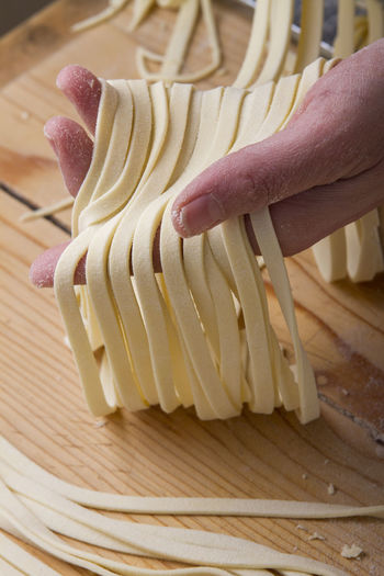 Cropped hand holding raw pasta on table