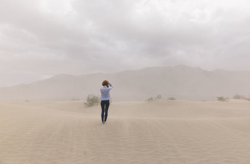 Rear view of woman standing in desert