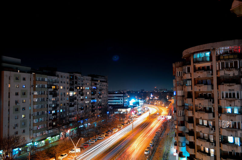 Light trails on road amidst buildings in city at night