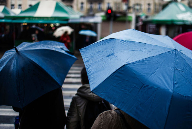 People with umbrellas on street in city during rainy season