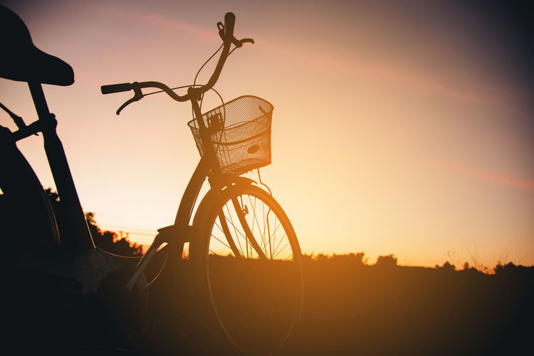 Silhouette of bicycle on road against sky during sunset