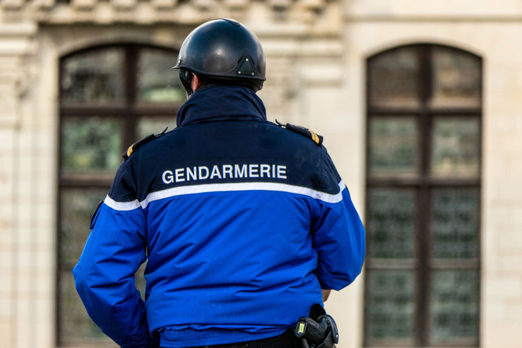 French gendarme on a horse seen from behind with inscription gendarme on his jacket