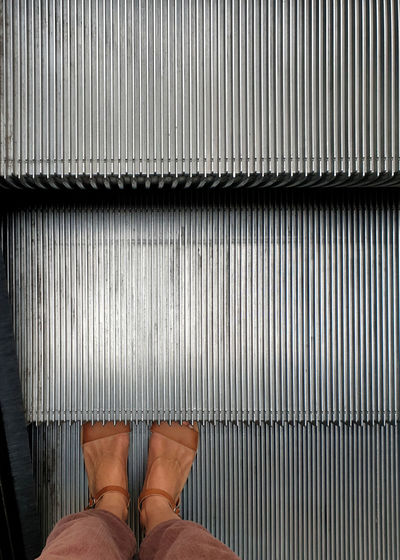 Personal perspective, woman wearing casual footwear standing on escalator step