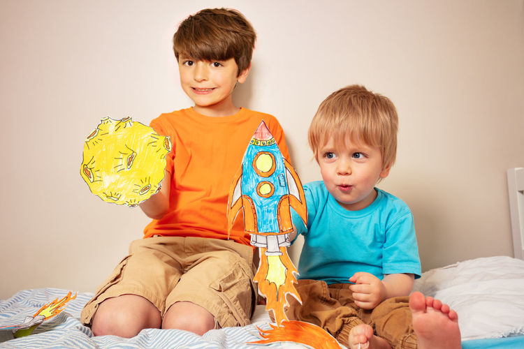 Boy playing with toy while lying on bed at home