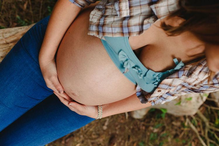 Midsection of pregnant woman sitting outdoors