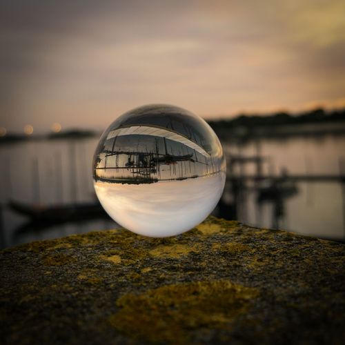 Close-up of crystal ball on lake against sky during sunset