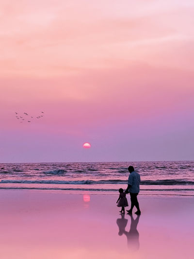 Man on beach against sky during sunset