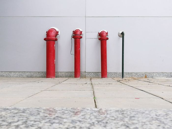 Footpath against red pipes on wall