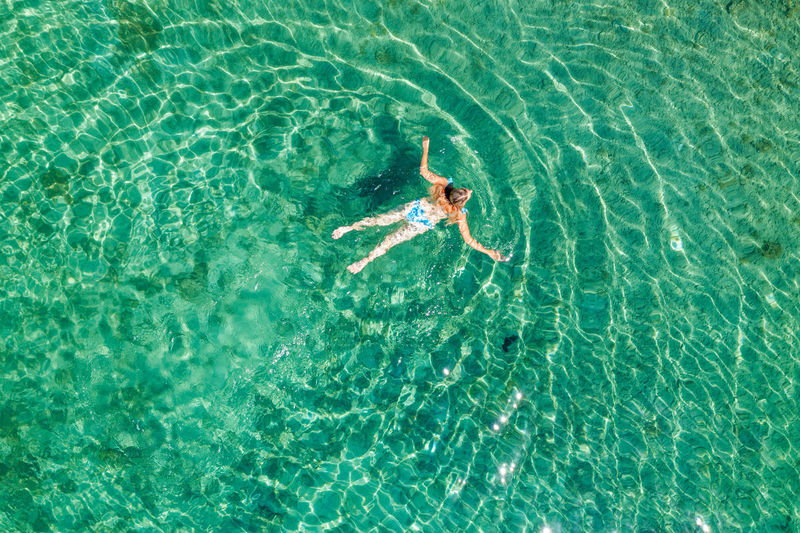 Aerial view of a girl floating in the turquoise sea on the cres island, adriatic sea, croatia