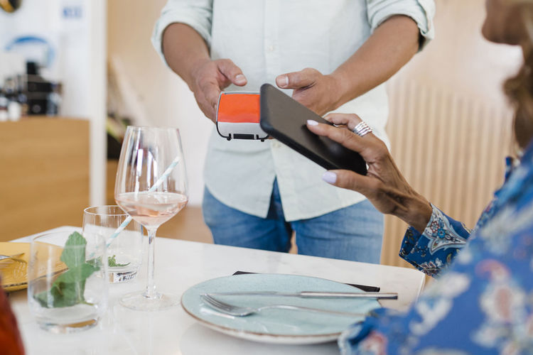 Mature businesswoman making payment through smart phone at restaurant