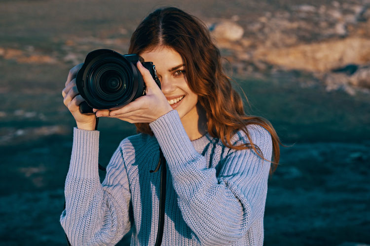 Portrait of young woman photographing with camera