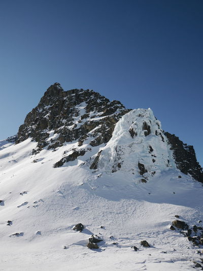 Scenic view of snow covered mountains against blue sky