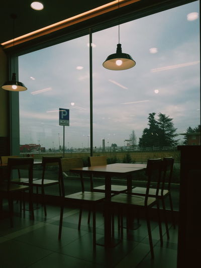 Empty chairs and table in restaurant against sky