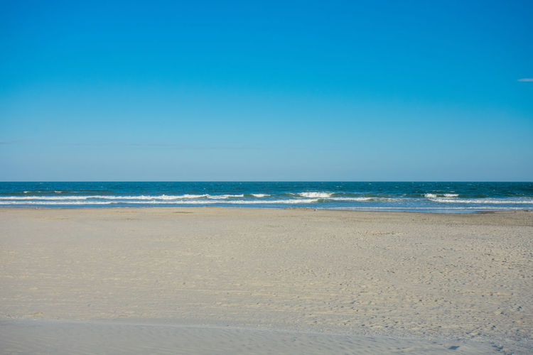 An empty beach and ocean with a clear blue sky behind at wildwood new jersey