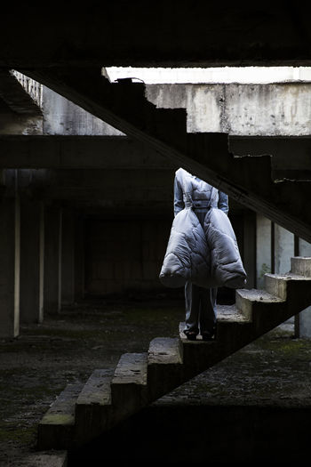Rear view of woman standing on staircase in abandoned building