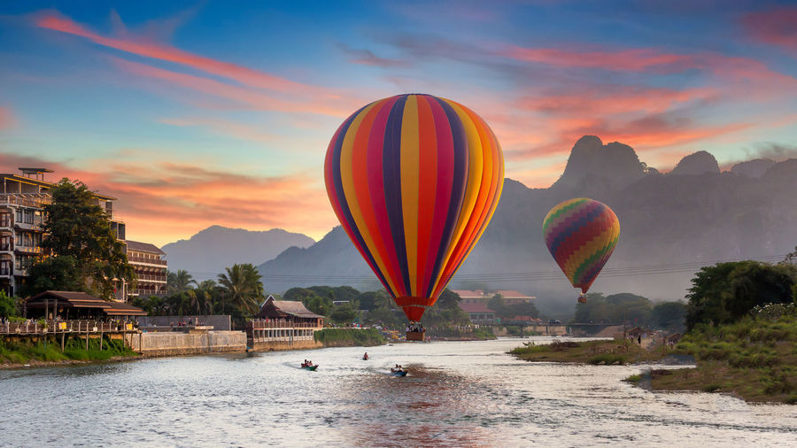Hot air balloon flying over water against sky during sunset