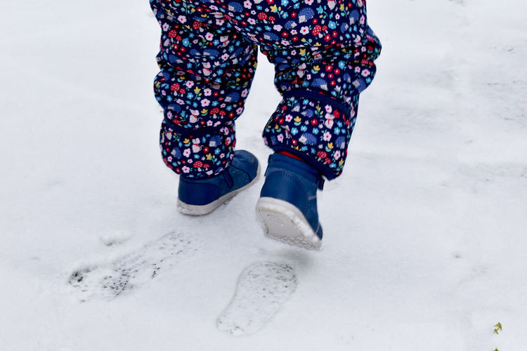 Low section of person standing on snow covered field