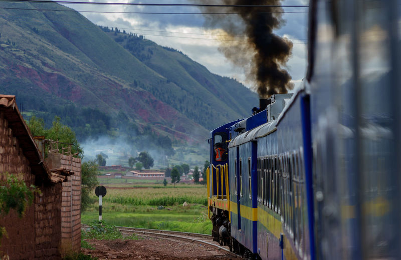 Train on field by mountains against sky