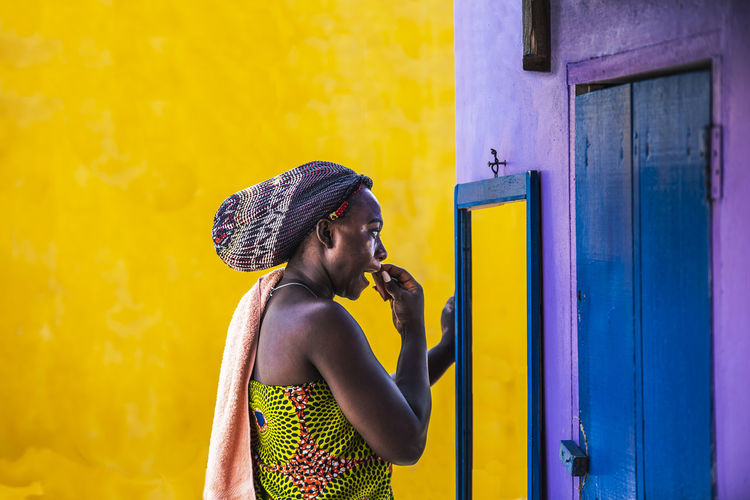 African woman with headdress stands outdoors and cleans off make-up in the small village of ghana 