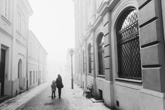 Woman and child walking on road in city