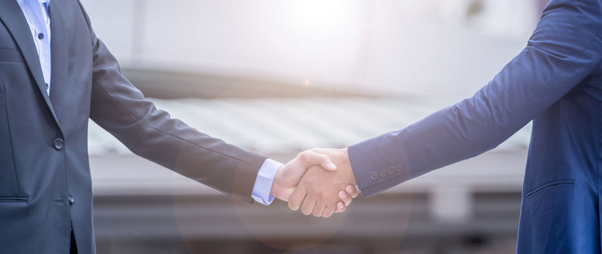 Midsection of businessmen shaking hands in city