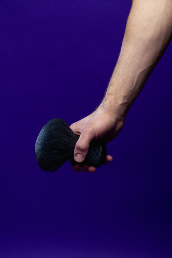 Low section of man holding microphone against blue background