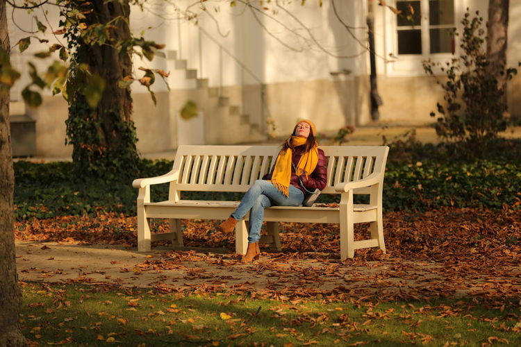 Woman sitting on bench in park during autumn