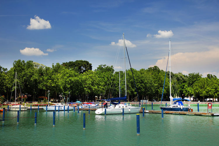 Boats moored at harbor against blue sky