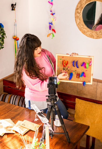 Side view of young woman photographing on table