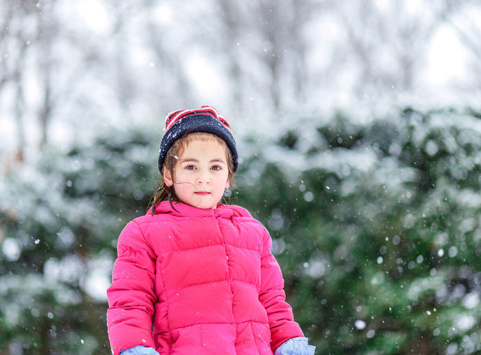 Young girl child standing in snow during light flurries on cold winter day