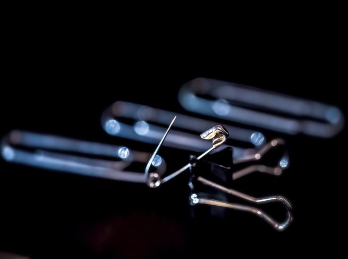 High angle view of office supplies and safety pin on black background