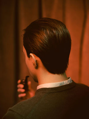 REAR VIEW OF YOUNG MAN LOOKING AWAY