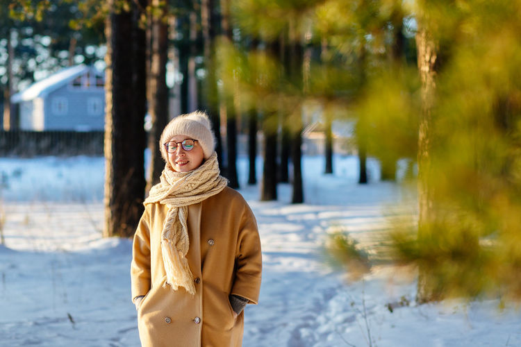 Portrait of woman standing by tree during winter