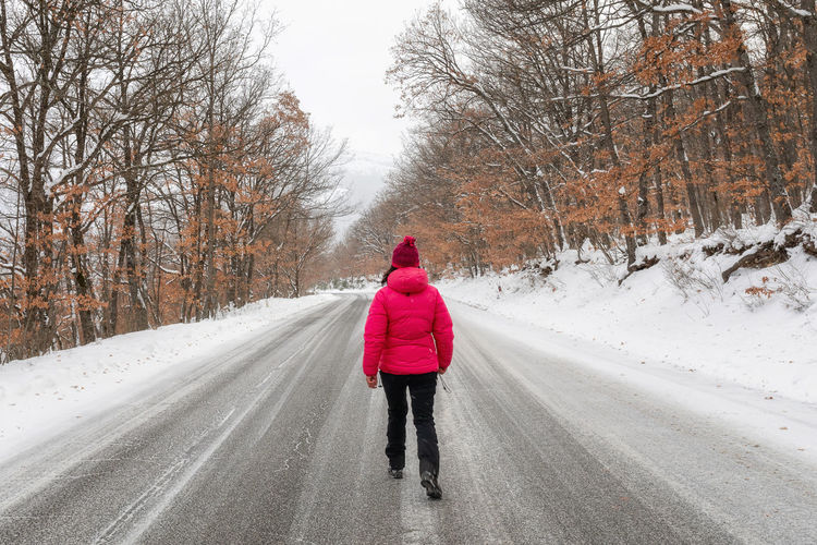 Rear view of woman on snow covered road