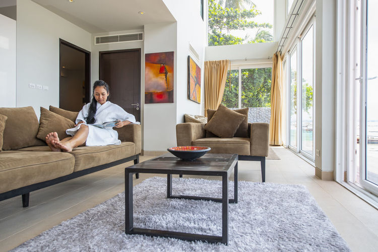 Beautiful woman reading at living room of luxury villa in phuket