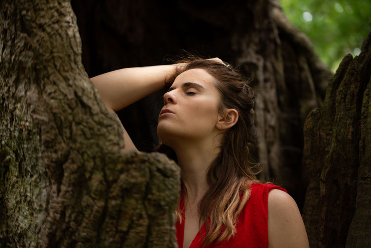 Young woman with eyes closed by tree