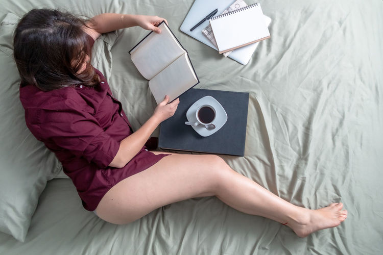 High angle view of woman using mobile phone on bed