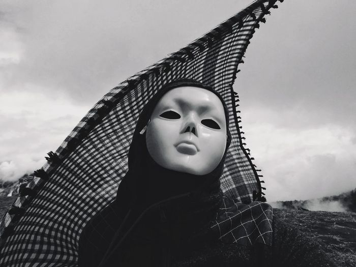 Close-up of person wearing mask against sky